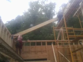 Carpenter raising a rafter beam on a new second story frame in Sequatchie