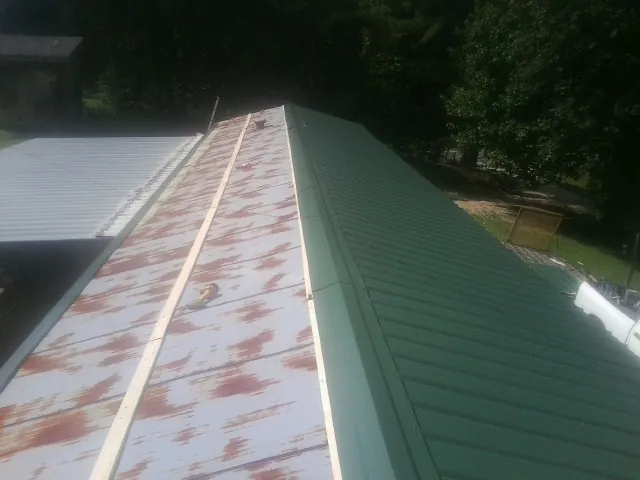 Old rusted panels beside newly installed green metal roofing — Wind Damage Roof Repair by Roofing Brothers in Sequatchie