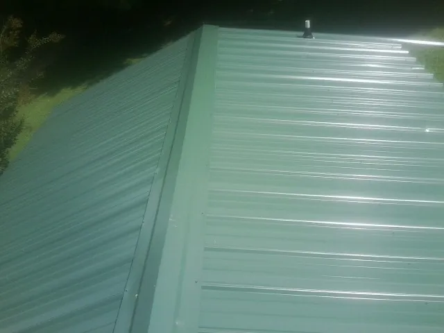 New green metal panels meeting at the ridge of a roof — Flat Roof Repair work by our crew in Sequatchie
